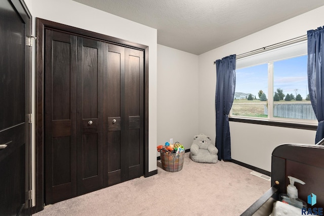 bedroom featuring light colored carpet, a textured ceiling, and a closet