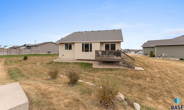 back of property featuring a wooden deck and a lawn