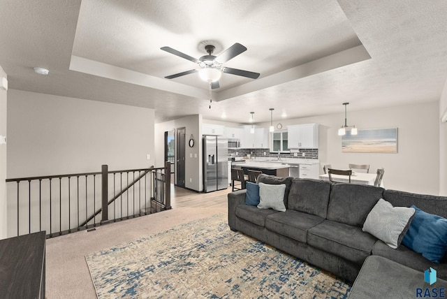 living room featuring a textured ceiling, a raised ceiling, and ceiling fan