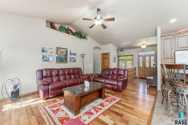 living room with ceiling fan, vaulted ceiling, and light wood-type flooring