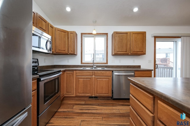 kitchen with decorative light fixtures, stainless steel appliances, dark hardwood / wood-style floors, and sink