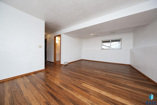 empty room featuring a textured ceiling and dark hardwood / wood-style floors