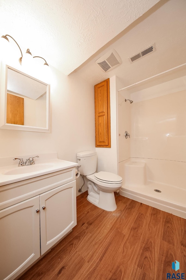 bathroom with hardwood / wood-style flooring, toilet, a textured ceiling, and walk in shower