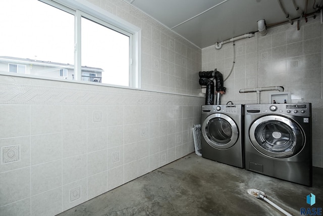 clothes washing area featuring washer and dryer and tile walls