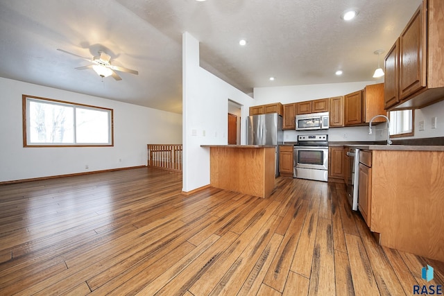 kitchen featuring appliances with stainless steel finishes, dark hardwood / wood-style floors, vaulted ceiling, and ceiling fan