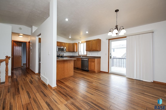 kitchen featuring pendant lighting, lofted ceiling, appliances with stainless steel finishes, and a chandelier