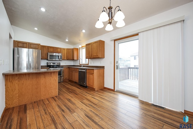 kitchen with hanging light fixtures, stainless steel appliances, dark hardwood / wood-style floors, a chandelier, and lofted ceiling