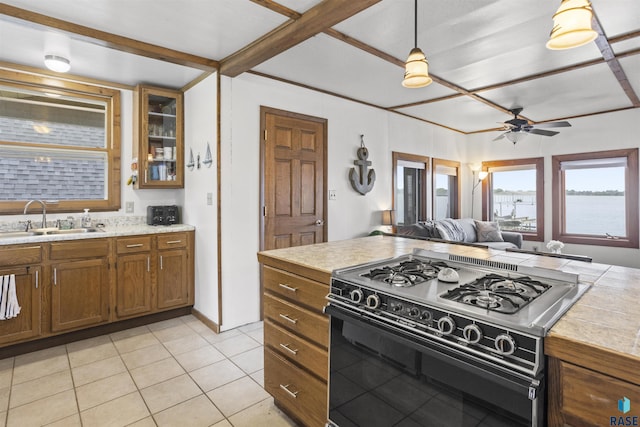 kitchen with pendant lighting, sink, ceiling fan, light tile patterned floors, and gas stove