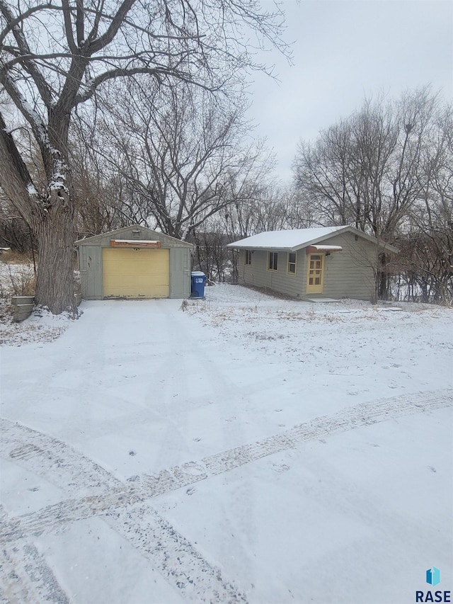 snowy yard featuring an outbuilding and a garage