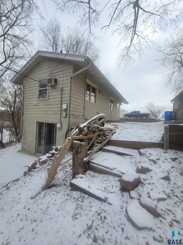 view of snow covered exterior with a wall mounted AC