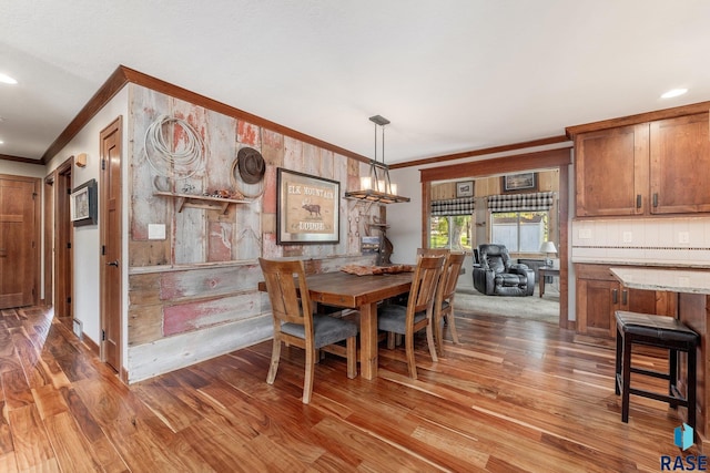 dining room with crown molding, wooden walls, and wood-type flooring