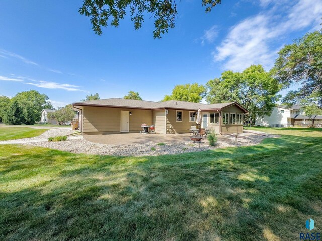 back of house with a lawn, a sunroom, and a patio