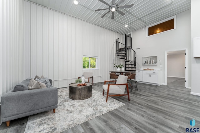 living room featuring wood-type flooring, a towering ceiling, and ceiling fan