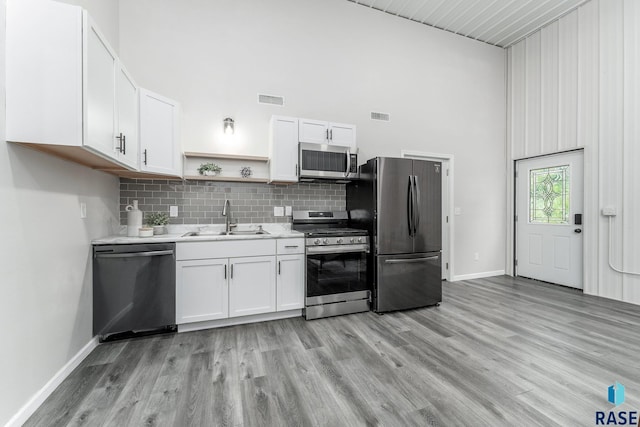 kitchen with sink, white cabinets, a high ceiling, and appliances with stainless steel finishes