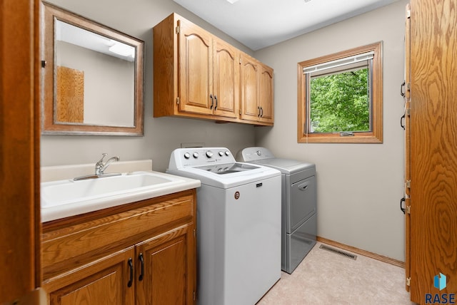 laundry area with washing machine and clothes dryer, cabinets, and sink