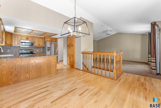 kitchen featuring tasteful backsplash, light hardwood / wood-style flooring, kitchen peninsula, vaulted ceiling, and appliances with stainless steel finishes