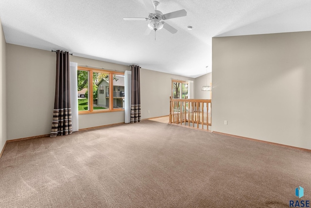 carpeted empty room with a textured ceiling, ceiling fan, and lofted ceiling