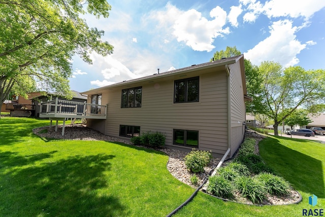 rear view of house featuring a lawn and a wooden deck