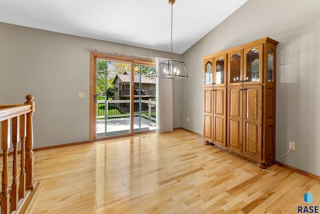 unfurnished dining area with light hardwood / wood-style flooring, lofted ceiling, and an inviting chandelier