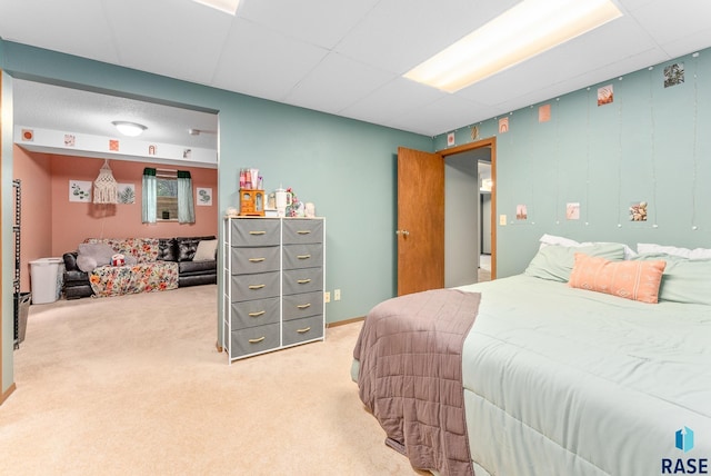 carpeted bedroom featuring a drop ceiling