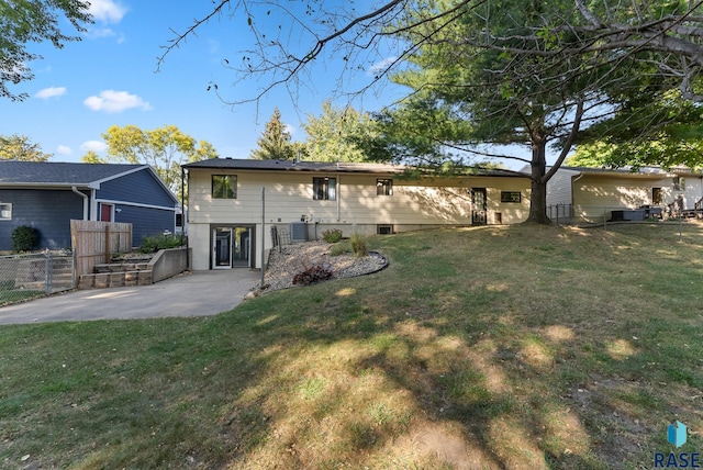 back of house featuring cooling unit, a patio area, and a yard