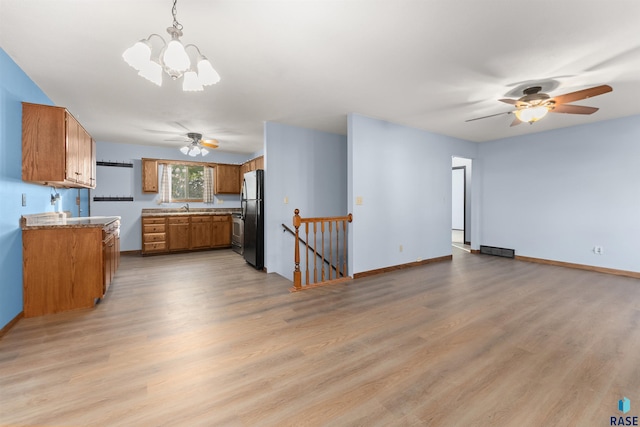 kitchen featuring ceiling fan with notable chandelier, refrigerator, decorative light fixtures, and light hardwood / wood-style floors