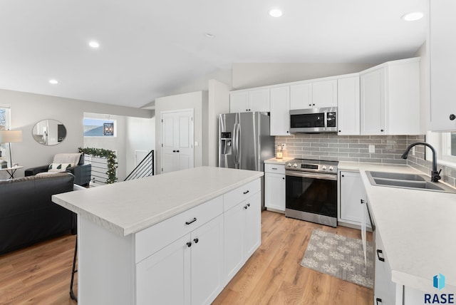 kitchen with white cabinets, stainless steel appliances, a kitchen island, and sink