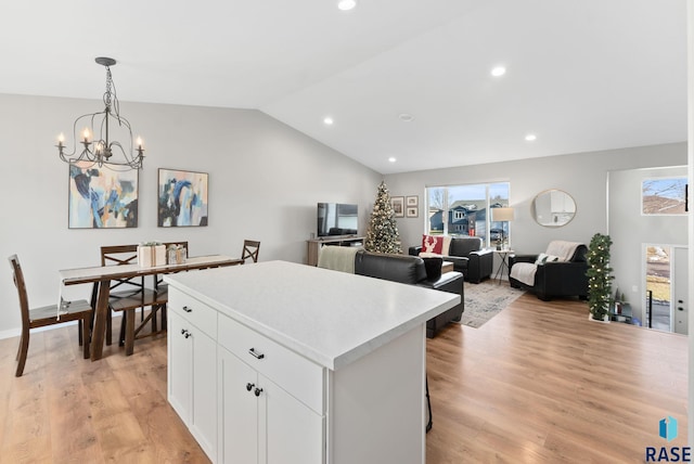 kitchen featuring a center island, light hardwood / wood-style flooring, a notable chandelier, decorative light fixtures, and white cabinets