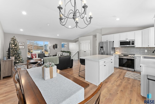 kitchen with a center island, pendant lighting, decorative backsplash, white cabinets, and appliances with stainless steel finishes