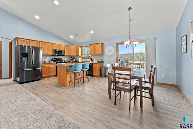 dining space featuring high vaulted ceiling, light hardwood / wood-style floors, and an inviting chandelier