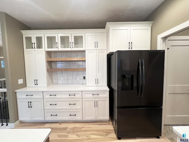 kitchen with black refrigerator with ice dispenser and white cabinets