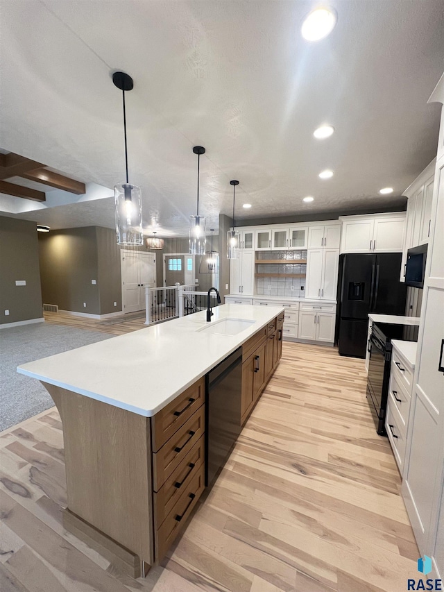 kitchen with black appliances, a large island with sink, and white cabinets