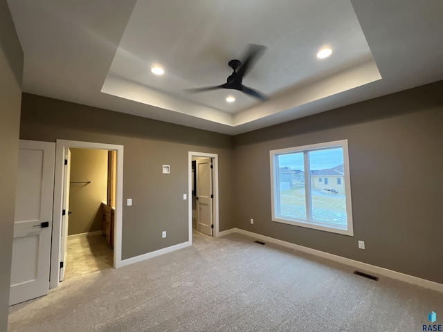 unfurnished bedroom featuring a spacious closet, a raised ceiling, and a closet