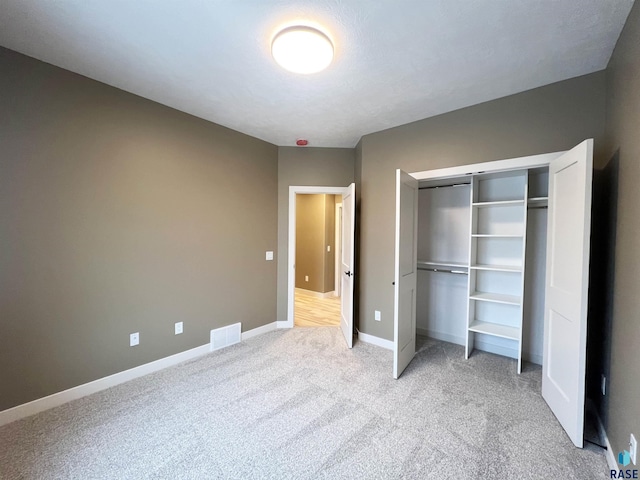 unfurnished bedroom featuring light colored carpet and a closet