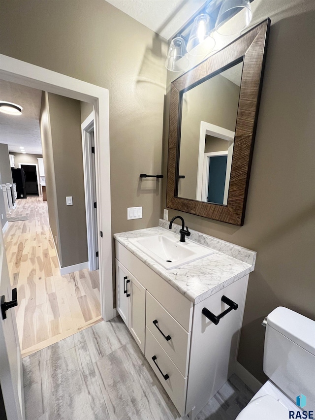 bathroom with wood-type flooring, toilet, vanity, and a textured ceiling