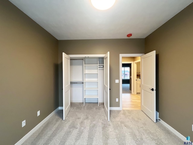 unfurnished bedroom with light carpet and a closet