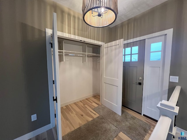 entrance foyer with an inviting chandelier, a textured ceiling, and light wood-type flooring