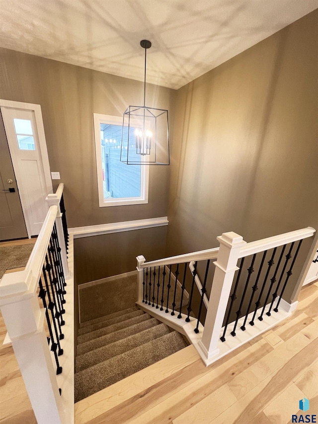 staircase featuring wood-type flooring and a chandelier