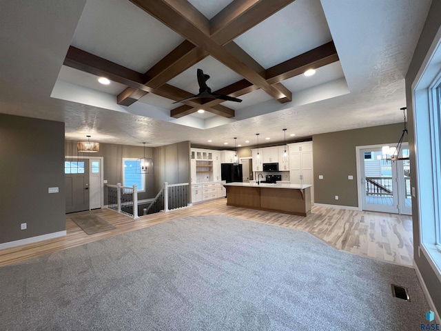 interior space featuring pendant lighting, coffered ceiling, a large island, and black fridge