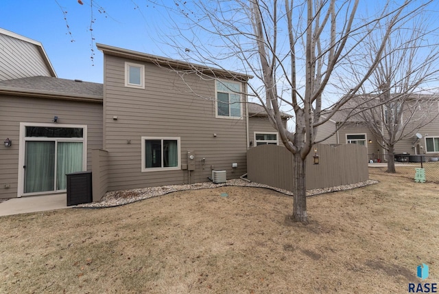 back of property featuring central AC unit and a lawn