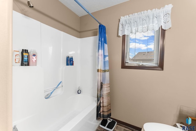 bathroom featuring a textured ceiling, shower / tub combo, and toilet