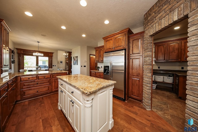 kitchen featuring stainless steel refrigerator with ice dispenser, a kitchen island, dark hardwood / wood-style flooring, and hanging light fixtures