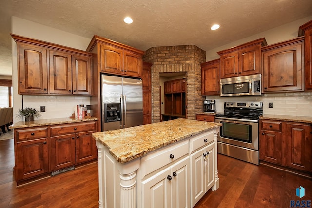 kitchen featuring light stone counters, dark wood-type flooring, stainless steel appliances, decorative backsplash, and a kitchen island