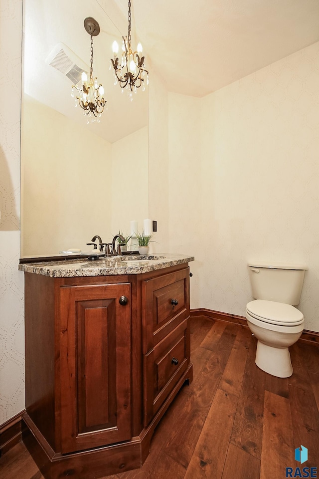 bathroom with toilet, vanity, hardwood / wood-style floors, and a notable chandelier