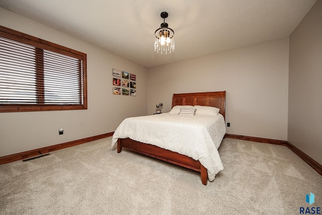 bedroom with light colored carpet and a chandelier