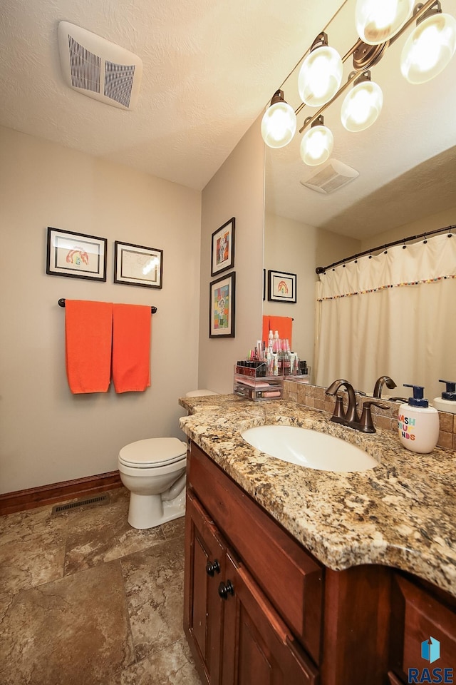 bathroom featuring toilet, vanity, and a textured ceiling