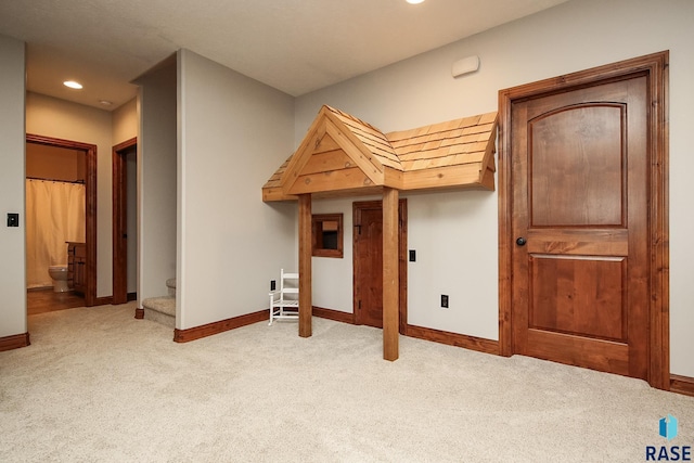 interior space featuring ensuite bath and light colored carpet