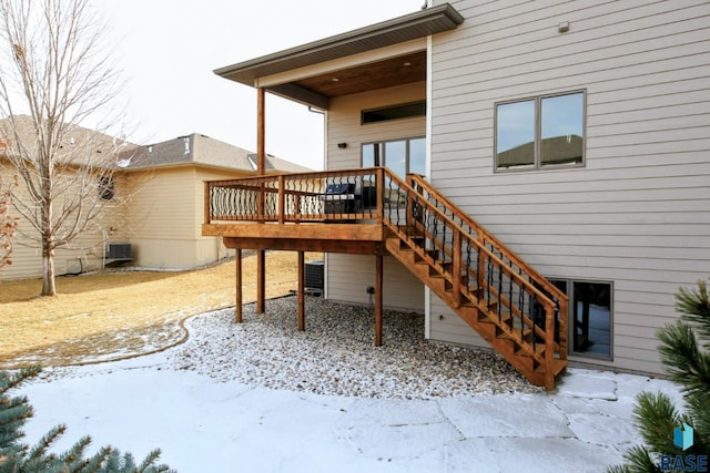 snow covered property with central air condition unit and a wooden deck