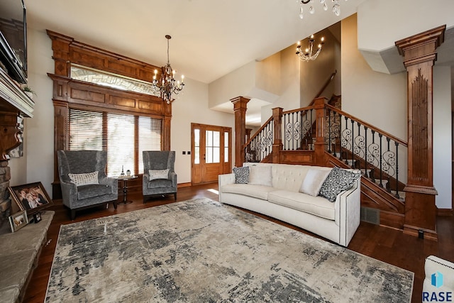 living room with a high ceiling, a chandelier, decorative columns, and dark hardwood / wood-style floors