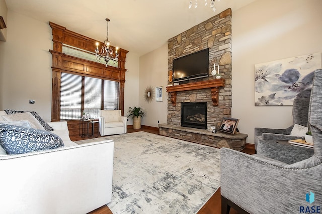 living room with wood-type flooring, a chandelier, and a stone fireplace